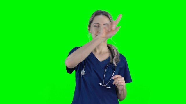 4K female nurse doctor on green screen isolated with chroma key. Woman pressing buttons on virtual screen. Copy space for animation, text or image. Touchscreen gestures