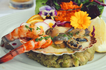 Delicious seafood dish from traditional cuisine of Madeira island - a mix of grilled shrimps, shells, mussels served with fresh orange, radish and mashed celery puree