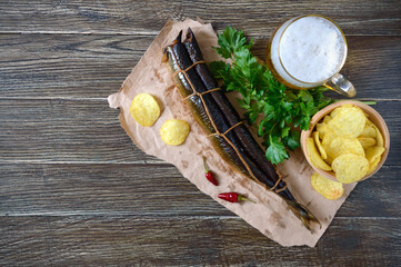 Beer snacks. Smoked fish, chips, a glass of lager beer on a wooden table