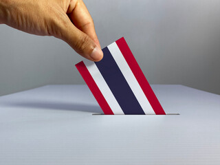 Voting / election concept: hand holding voting card with country national flag, inserting it into...