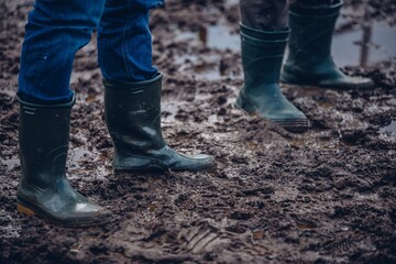 Shallow focus shot of people in rubber boots standing in the mud
