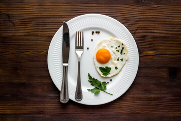 Fried eggs on plate - dark wooden table top view