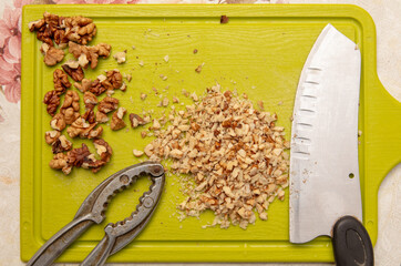 Knife-chopped walnuts on a green plastic board.