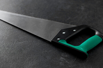 work tools, carpentry equipment and instrument concept - close up of saw on slate background