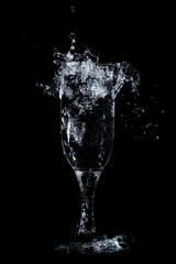 Splashes and drops of water in a glass are isolated on a black .