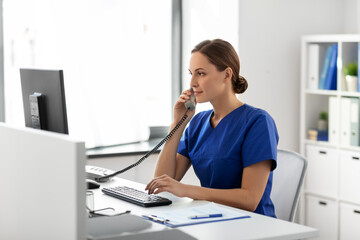 medicine, technology and healthcare concept - female doctor or nurse with computer calling on phone...