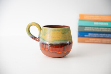 colorful handmade ceramic coffee cup with books on the table