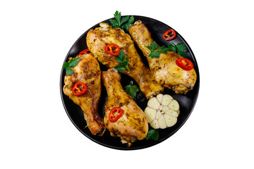 Roasted chicken drumsticks with spices in a black plate isolated on white background. Top view
