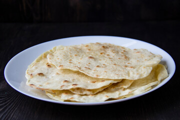Delicious pita bread made at home in a pan. Thin pita bread on a white plate