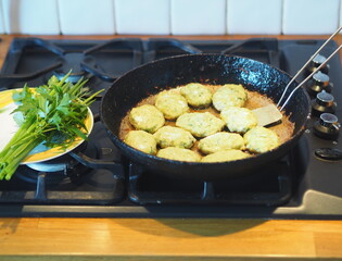 Vegetarian fish and vegetable cutlets are fried in a black pan on the kitchen stove. Healthy home food.