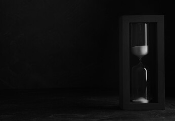 Sandglass on table against black background, space for text. Pareto principle concept