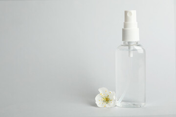 Antiseptic spray and flower on light grey background, space for text