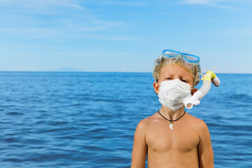 Boy in snorkeling mask wear surgical face mask on sea beach. Cancelled cruises, tours due coronavirus COVID 19 world epidemic. Travel ban for family vacation, tourism industry crisis at summer 2020
