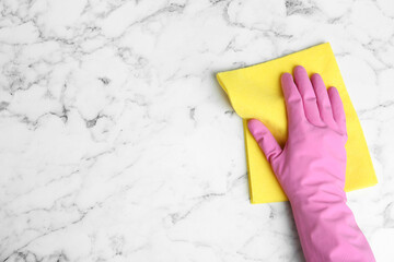 Woman in gloves wiping white marble table with rag, top view. Space for text