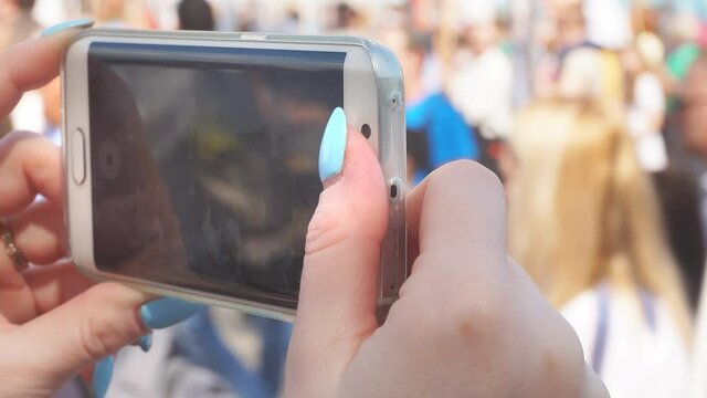 Russia, Ufa - 9 may 2019: Close-up of a woman's hand holding a smartphone, a woman films the victory day parade. Close-up of a woman's hands holding a cell phone, takes a video on a smartphone.