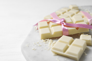 Tasty white chocolate with ribbon on wooden table, closeup