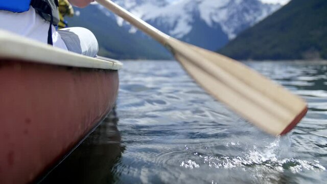 Closeup of Paddles rowing a canoe towards Mountains