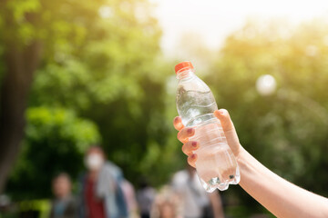 Woman holding bottle of clean water on a city street at summer