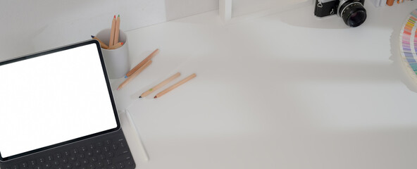 Designer office desk with mock-up tablet, camera, designer supplies and copy space on white table © bongkarn