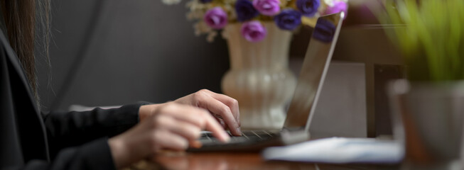 Side view of businesswoman typing on laptop on wooden counter bar