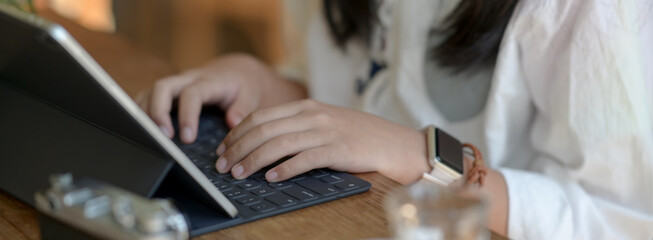 Close up view of female freelancer typing on tablet keyboard