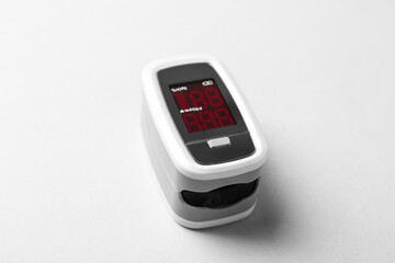 Modern fingertip pulse oximeter on white background, closeup