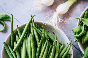 Haricots verts frais et oignons grelot sur la table de cuisine
