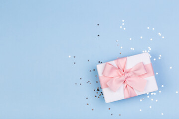 Gift or gift box and stars confetti on a blue table from above. Flat composition for birthday