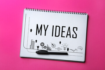 Notebook with words NEW IDEAS and pen on pink background, top view