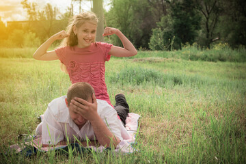 Fototapeta premium Happy man with children in the park. Portrait of children and father lying on the grass on a clear sunny day. A family. Father's day.