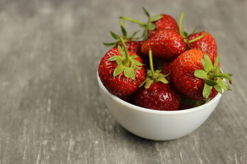 Strawberries ripe in a plate on a gray background