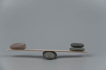 Balance, misbalance and disbalance concept. Zen stones on wooden seesaw. Concept of harmony, calm, yoga and meditation, spa, massage, relax. Zen garden.