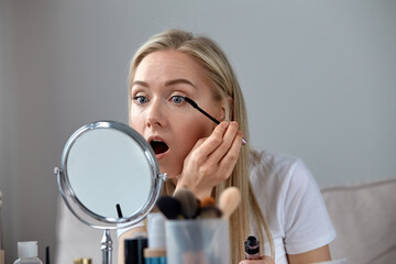 A young girl with an open mouth paints the restwomen with black ink.
