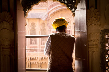 Indian man looking out the window in Mehrangarh Fort, Rajasthan, India