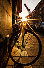 Rays of sun coming through the bicycle silhouette, bike at sunset.