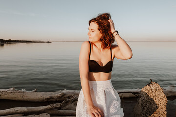 Posing woman in nature. Young woman in stylish clothes:  top and white skirt  posing against the backdrop of a  sea. Photos on vacation in the fall