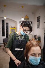 Hairdresser and customer in a salon with medical masks during virus pandemic. Working with safety mask.