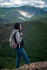 Naklejka premium Young traveling woman on the top of the mountain cliff