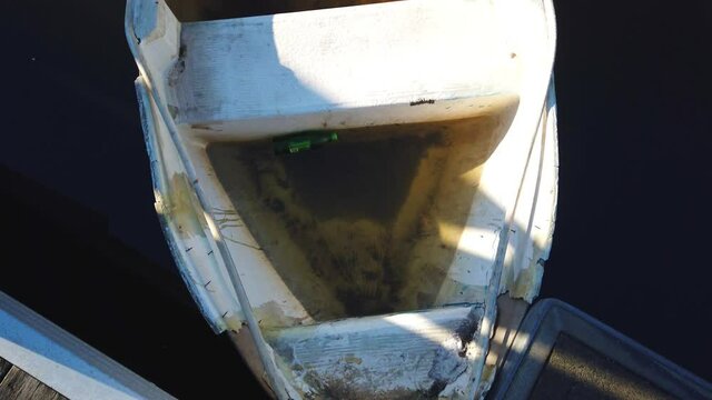 Leaked junk small mini fishing boat flooded with dirty rain water and mud by the deck