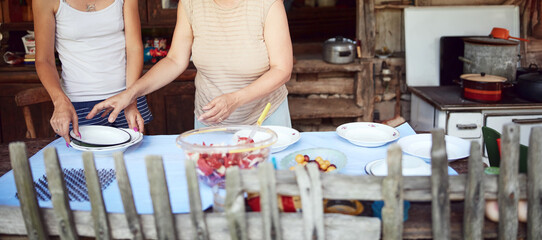 Family preparing food and feast for summertime lunch at countryside rustic cottage outdoor kitchen.