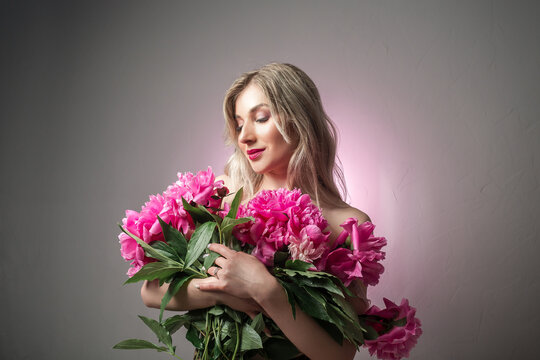 Portrait of beautiful young woman with pink peonies. Spring summer skincare beauty, spa and body care concept