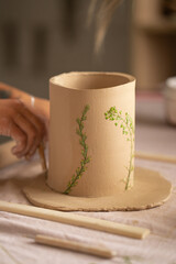 The potter's woman hands are shaped a cup from a clay at the workshop. The potter's woman hands are shaped a cup from a clay. The process of creating pottery. 
