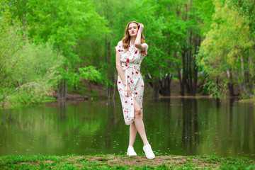 Portrait of a young beautiful woman in white dress posing by the lake