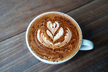 Close up ceramic cup of hot Chocolate cocoa in heart tulip shape on wooden table