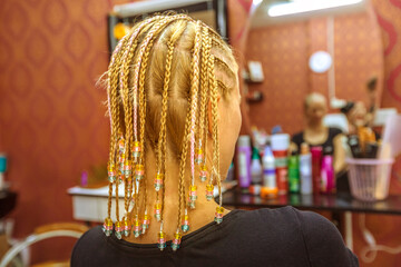 Close up pearl braids to a young blonde woman with dreadlocks in a Thai beauty center, looking the...