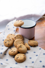 different cookies on napkins and wooden background with a pink cup with milk
