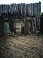 Fototapeta na wymiar high fence, wood and concrete, in gray terrain, in moody colors