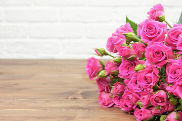 Bouquet of pink roses on a white brick wall background with copy space. The concept of flowers, floristry, holiday