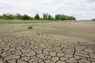 dry pond with cracked earth against a cloudy sky 8