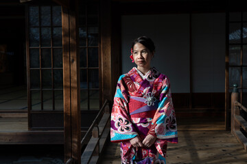 Woman dress in pink kimono walking in Japanese house with dark background.